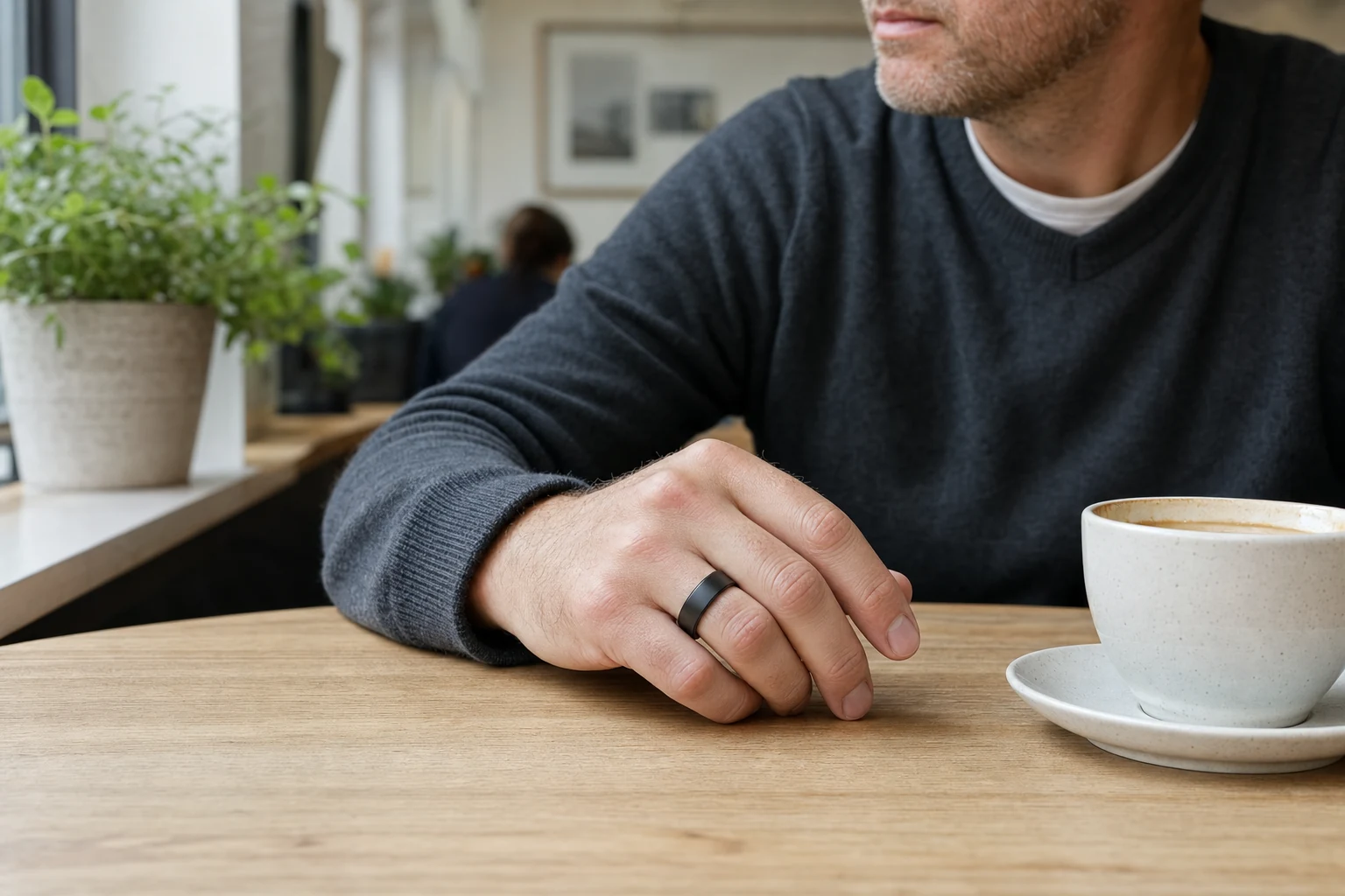 Man wearing a Smart Ring at a cafe table