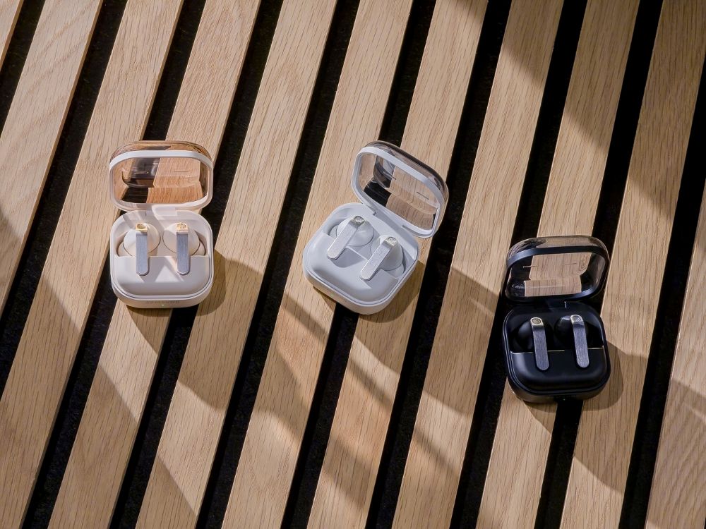 Samsung Galaxy Buds4 Pro charging cases in three colours on a wooden bench